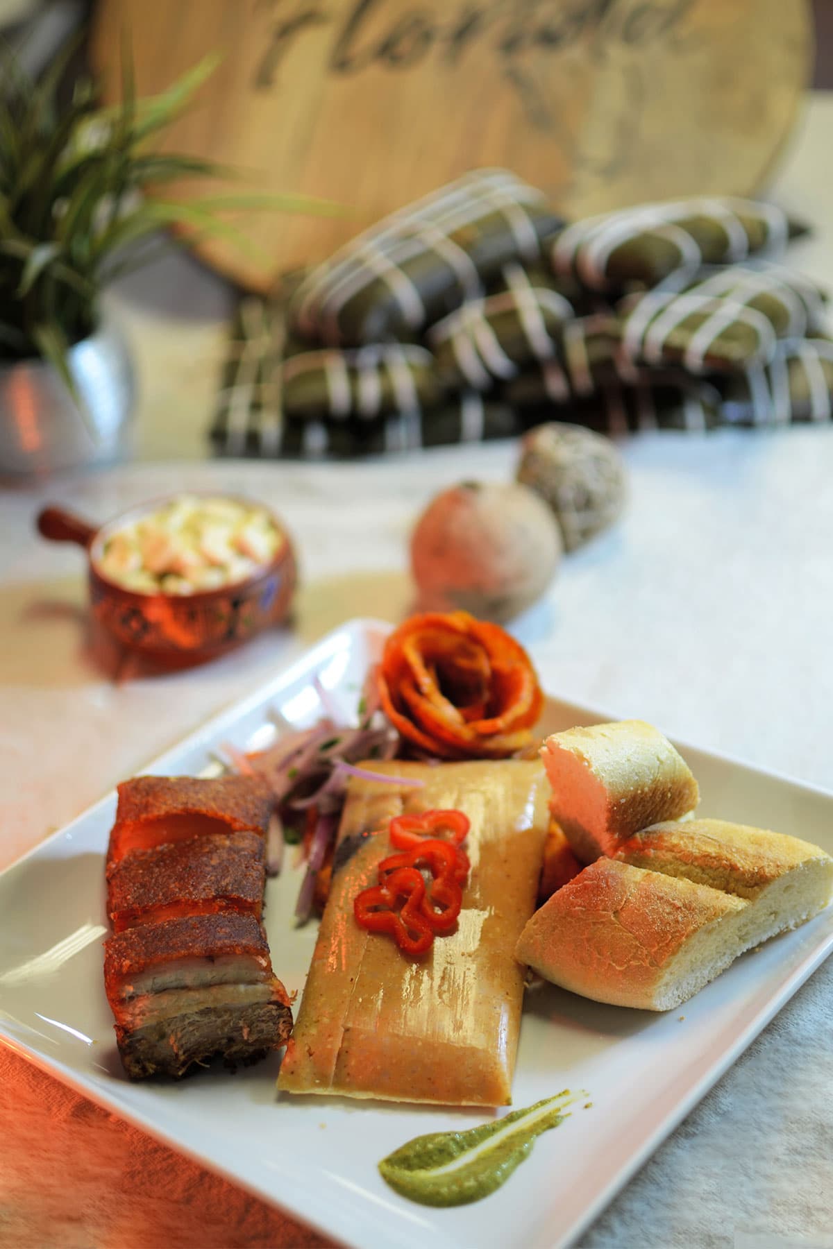 Hand-wrapped tamales in a basket on a wooden tray